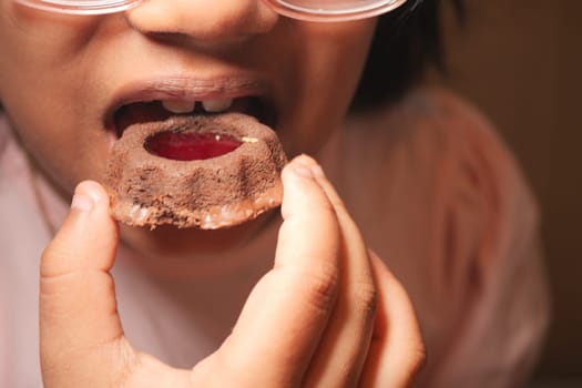 A young child holds a sweet treat, ready to take a bite with excitement.