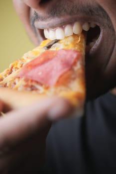 A person is about to take a big bite of cheesy pepperoni pizza.