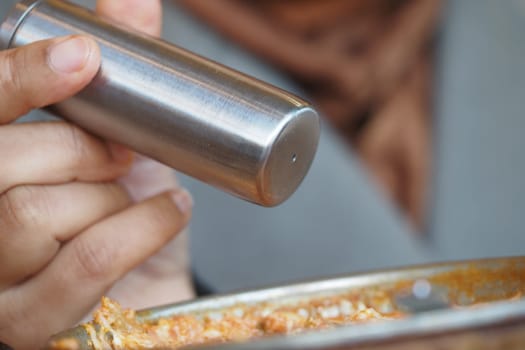 Close-Up of a Hand Holding a Stainless Steel Spice Shaker.