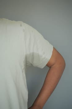 A person stands with one arm resting at their side, showing sweat marks.