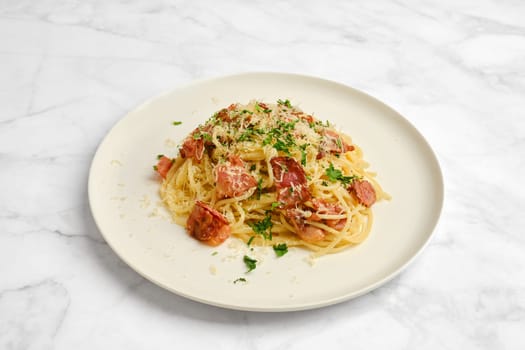 Spaghetti carbonara on a white plate features tender noodles mixed with crispy bacon pieces and garnished with fresh herbs. The dish is inviting and ready to be enjoyed.