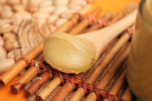 Creamy pistachio butter rests on a spoon amid scattered nuts and textures.