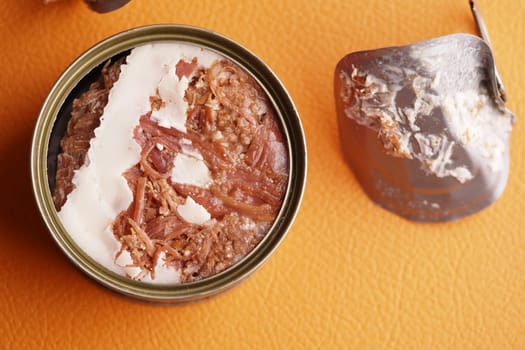 A savory meat spread stored in a tin, alongside a piece of its cover.