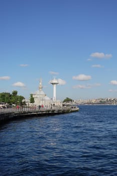 People stroll along the water's edge, enjoying the beautiful day in Istanbul.