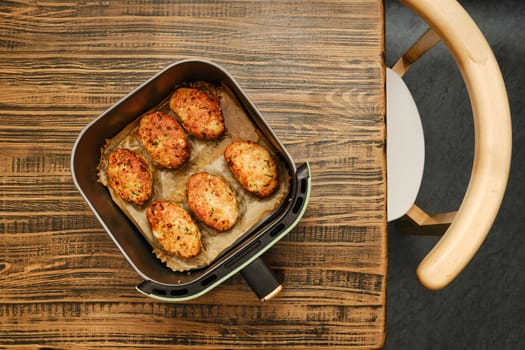 Roasted crispy meat patties in an air fryer basket, resting on a wooden table