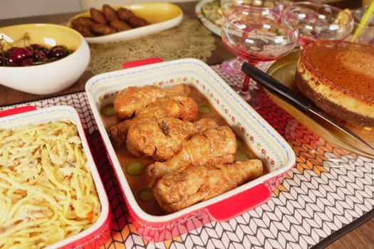 A table is filled with fried chicken, pasta, and cake.