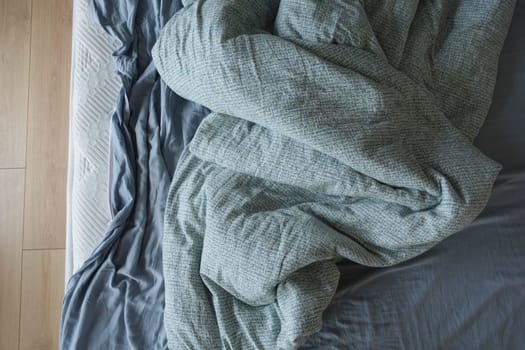messy bedroom setting with a rumpled blanket on a bed.
