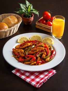 A vibrant dish of chicken fajitas features colorful bell peppers and spices, garnished with lemon slices.