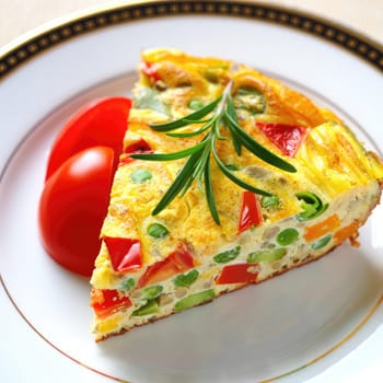 A slice of vegetable frittata showcases vibrant colors from peppers and green beans, garnished with fresh herbs, and accompanied by juicy tomato wedges on an elegant plate.