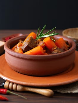 Hearty beef and carrot stew is beautifully presented in a traditional bowl. Fresh herbs add a pop of color, enhancing the inviting appearance of this comforting meal.