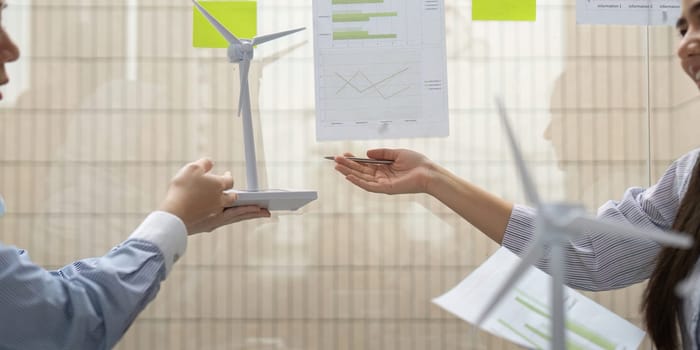 Two corporate professionals collaborate on renewable energy initiatives, exchanging models, and insights on sustainability metrics related to wind energy solutions.