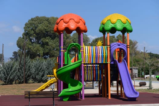 Brightly colored playground equipment stands tall against a vibrant blue sky, eagerly awaiting children to explore its many slides and climbing areas while enjoying a lovely sunny day.