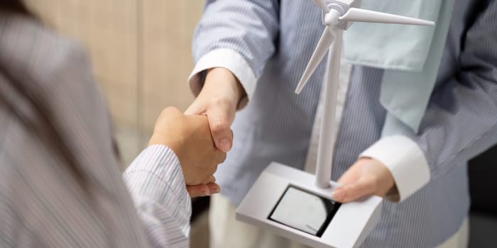 A close-up of a handshake conveys mutual agreement and commitment between two professionals discussing sustainable energy initiatives.