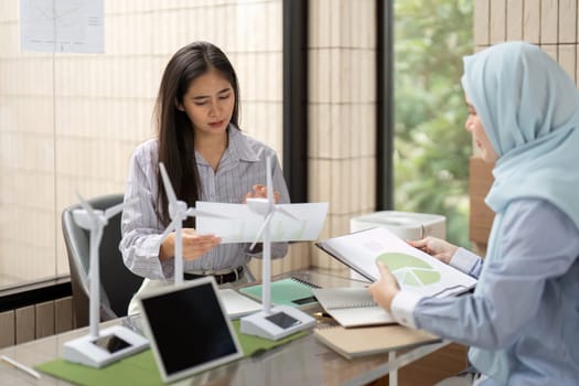Two professionals engage in detailed analysis and strategy discussion about sustainable energy practices, reviewing notes and models to drive innovative environmental solutions.