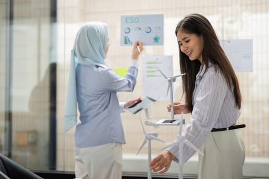 Two individuals illustrate the importance of teamwork by discussing ESG-related projects while showcasing renewable energy models.