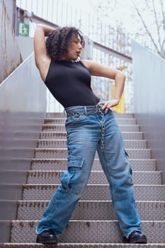 African American woman dancing in a creative pose between benches in an urban setting. he wears casual clothes and shows balance,strength, and expression. Concept of movement, art,and freedom.Vertical