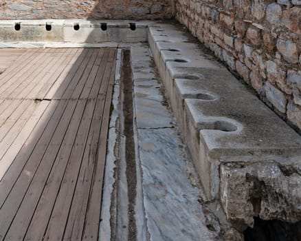 Remains of public latrines in Ephesus, Selcuk, Izmir, Turkey reveals how ancient Greeks managed sanitation. This archaeological site highlights communal facilities used for hygiene in a historic city