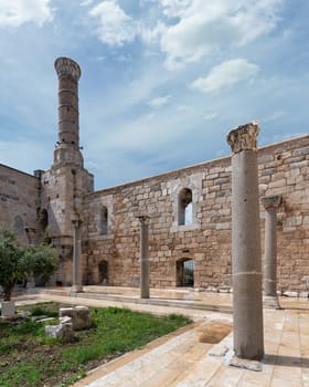 Courtyard of Isabey Mosque, in Selcuk, Izmir, Turkey, adorned with intricate architectural designs, featuring Roman columns and a tall minaret in Anatolian style, against the backdrop of a clear sky