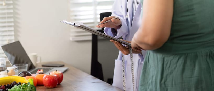 During a wellness checkup, a healthcare provider measures a patient's progress using a clipboard filled with health information, surrounded by nutritious foods.