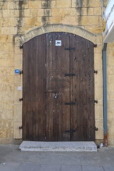 A sturdy wooden door stands closed against a weathered stone wall, adorned with iron hinges and a large padlock. Its rustic charm evokes curiosity about what lies beyond.