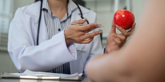 A doctor emphasizes the importance of balance in dietary choices by presenting both a dessert and a healthy apple to the patient.