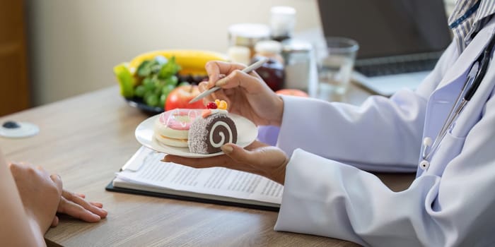 A healthcare professional offers a plate of delicious sweets while discussing the importance of balanced nutrition and making mindful choices during a wellness consultation.