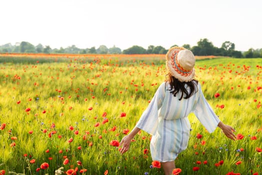 A happy young woman in a straw hat and a white dress who holds her hands in different directions, the sun is shining in her face, welcoming a new day, joy, happiness. Sunrise