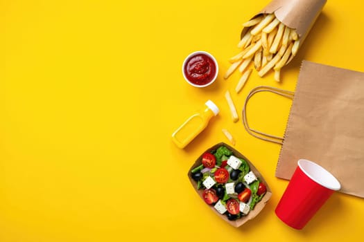 A colorful arrangement of delicious fast food items shows a bowl of salad, crispy fries, ketchup, and mustard on a bright yellow surface. The atmosphere radiates casual dining enjoyment.