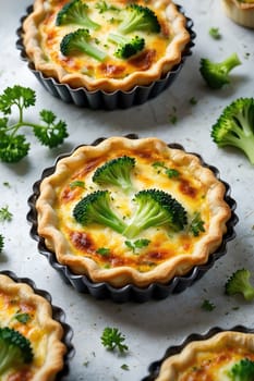 Tiny quiches filled with broccoli and cheese sit in black tart pans. Fresh herbs surround the quiches, adding vibrant color and flavor. Perfect for a light meal or appetizer.