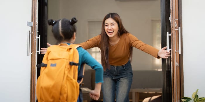 A delightful scene as a young girl enters her home, running into the arms of her parent, filled with warmth and excitement after a day at school.