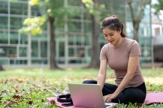 A woman enjoys a moment of digital productivity while comfortably seated outdoors, integrating her health routine with technology for a balanced lifestyle.