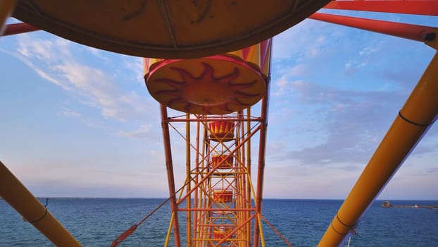 Colorful ferris wheel cabins overlooking the Black Sea under a blue sky with some clouds