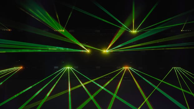 Green laser beams crossing each other during a music show in a dark concert hall
