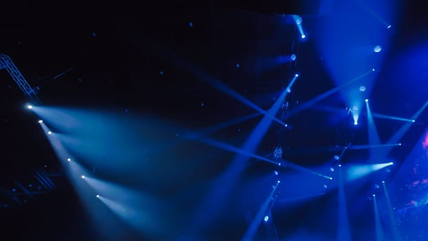 Bright blue spotlights shining in smoky concert hall during live music show