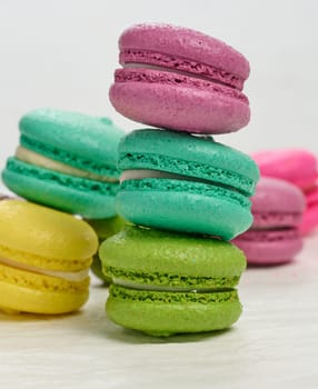 An assortment of colorful macarons on a white surface. The macarons have a smooth, delicate shell and a creamy filling
