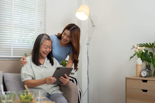 The mother and daughter share a lighthearted moment while looking at a tablet, celebrating technology as a way to foster family connections.