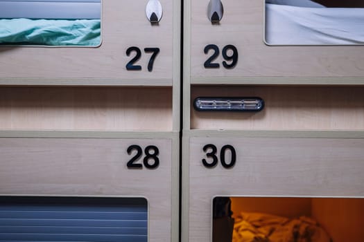 Close-up view of numbered sleeping pods in a contemporary capsule hotel, providing compact and affordable accommodation