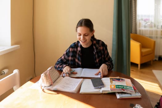 A student is seated at a wooden table, studying with open notebooks and textbooks. Sunlight filters through a window, creating a warm atmosphere.