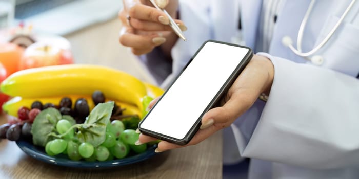 In a health consultation, a doctor utilizes technology to present nutrition information, emphasizing the importance of incorporating fresh fruits in dietary plans.