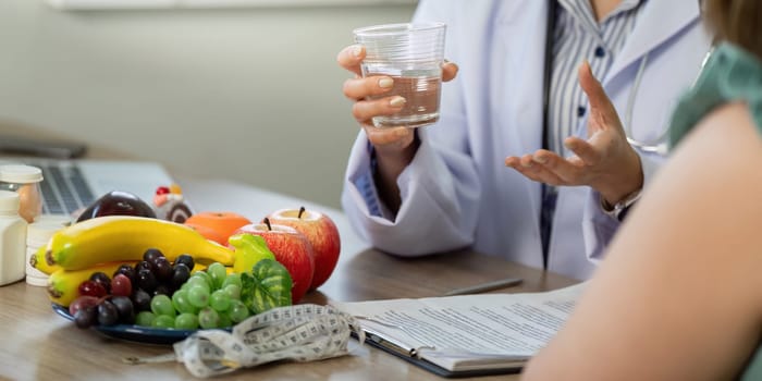 The doctor emphasizes the importance of hydration and nutrition, using fruits and health guidelines during a patient consultation.