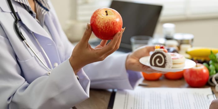 A doctor contrasts nutritious foods like apples with desserts, engaging in a meaningful conversation about making healthier dietary decisions with their patient.