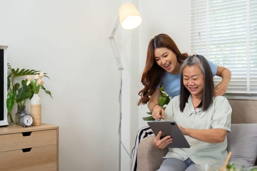 In a comfortable living room, a mother and daughter interact joyfully while exploring content together on a tablet, reinforcing their connection through technology.