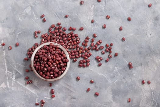 Ceramic bowl full of dried azuki beans on gray table top view. Healthy vegetarian food, legumes protein source. Traditional East Asiancousin ingredient