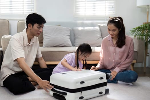 A mother, father, and their young daughter engage in a fun packing session at home, highlighting the excitement of preparing for family travel. The image captures laughter and togetherness.