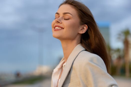 A woman in professional clothing standing confidently outdoors, embracing a moment of tranquility with a smile. Ideal for business, empowerment, and lifestyle concepts.