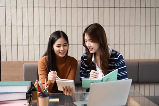 In a vibrant cafe setting, two students enthusiastically review their materials and share insights over their study notebooks.