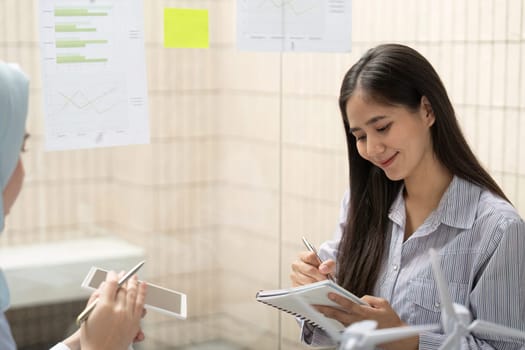 A focused meeting between two professionals emphasizes sustainable practices through collaborative brainstorming on ESG strategies, using visual aids and notes.