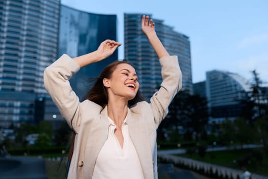 A vibrant woman in a light business outfit joyfully expresses success in a contemporary urban environment, reflecting confidence and a positive attitude.
