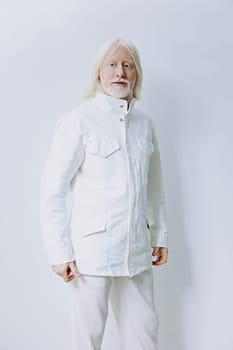 The image showcases an elderly man dressed in a stylish white jacket, set against a soft, light colored background His serene expression embodies sophistication and grace, perfect for themes of aging gracefully and contemporary style