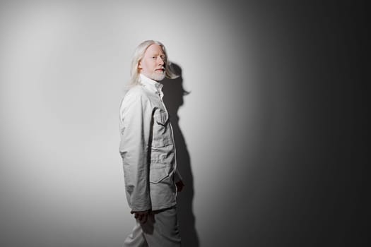 A captivating portrait of a man dressed in a sleek white ensemble, set against a gradient gray backdrop The subtle lighting casts intriguing shadows, emphasizing the subject s artistic expression while creating a serene atmosphere
